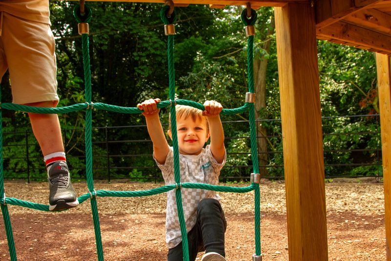 Child climbing a scramble net on the play area